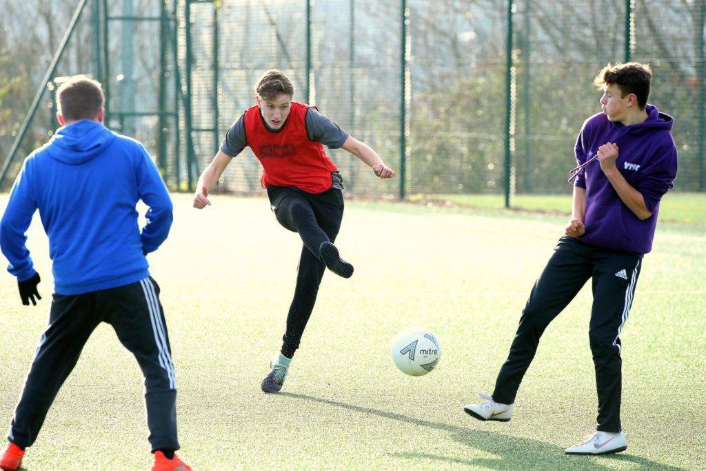 A group of three teenage boys are playing football