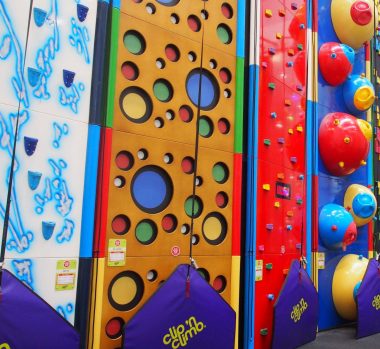 Colourful indoor climbing walls with various patterns and holds at YMCA Newark Clip 'n Climb facility.