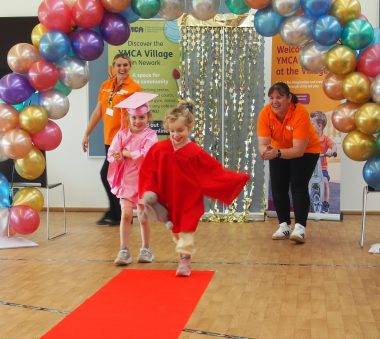 A child walks down a red carpet at the YMCA Nursery graduation